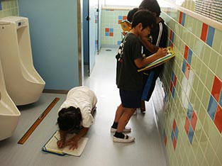 座り込んでトイレの寸法等を記録する子ども